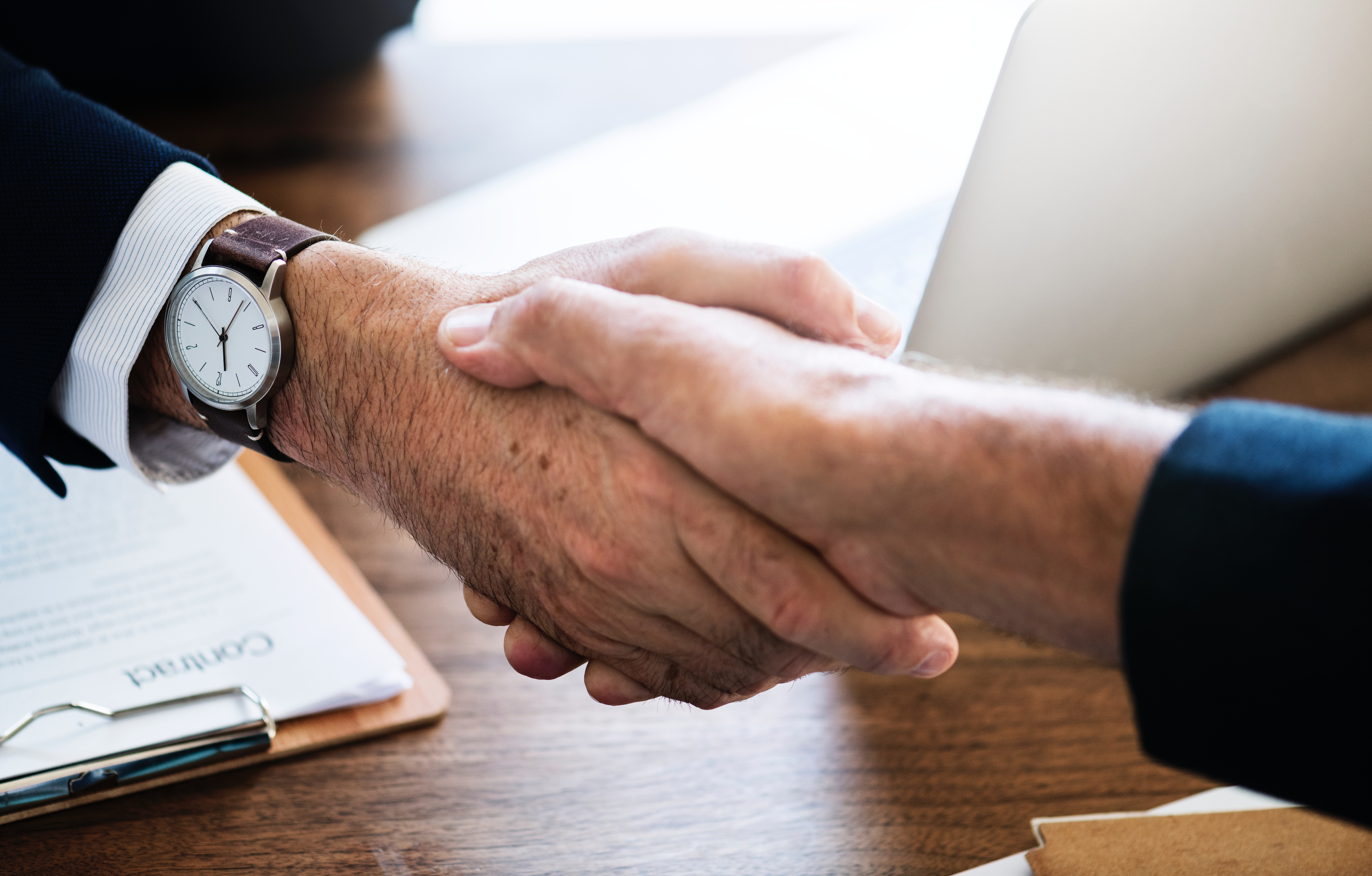 A job candidate and hiring manager shaking hands in a modern office after reaching agreement on an offer