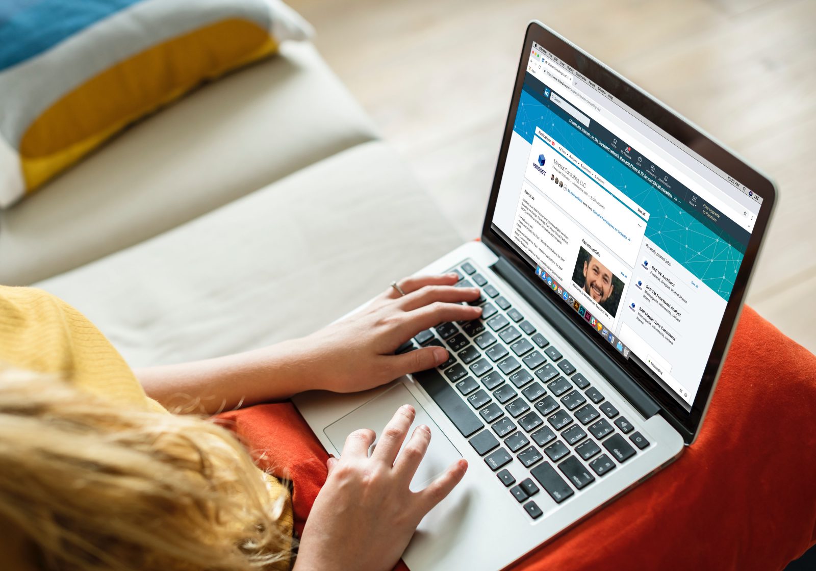 A job seeker sitting at a desk editing their LinkedIn profile on a laptop in a bright home office