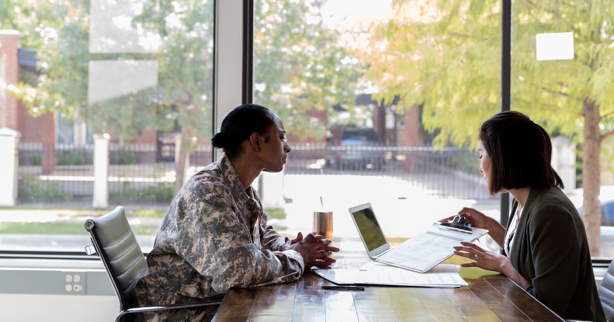 A military veteran in a suit holding a folder while waiting outside an office conference room, calm and professional