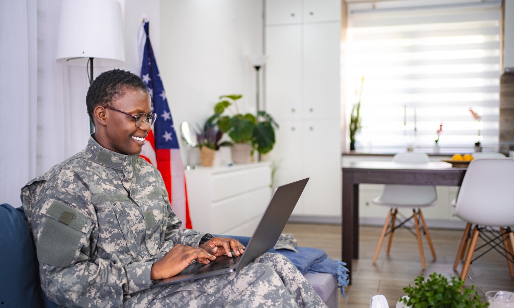 A military veteran in civilian clothing reviewing a LinkedIn profile on a laptop at a kitchen table